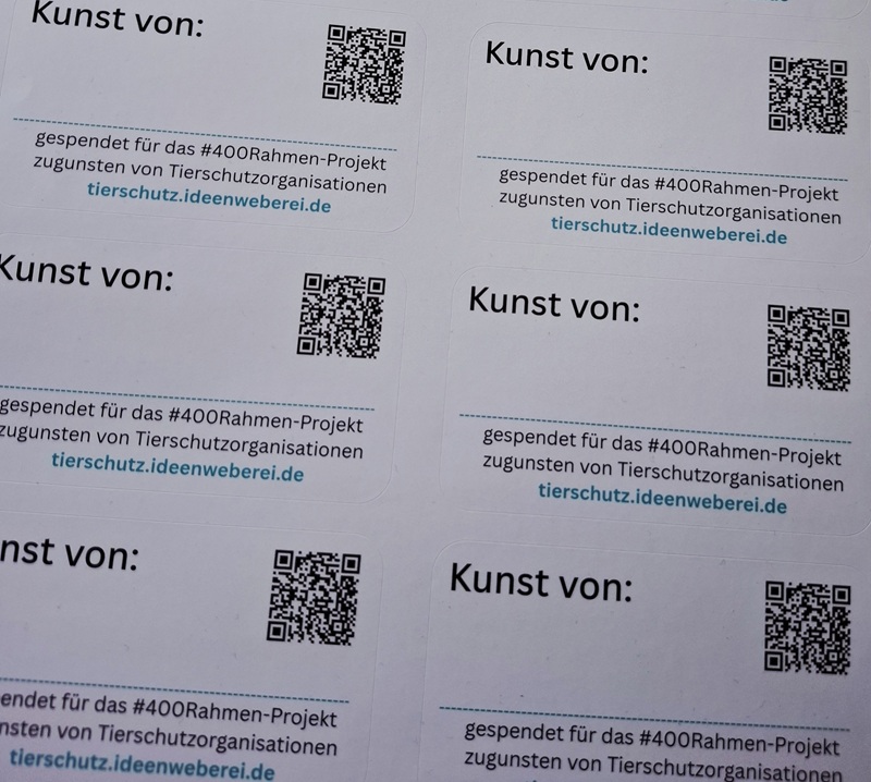 Mehrere gedruckte Aufkleber mit dem Text 'Kunst von:' und QR-Codes, darunter der Text 'gespendet für das #400Rahmen-Projekt zugunsten von Tierschutzorganisationen tierschutz.ideenweberei.de
