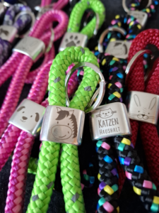 Mehrere Schlüsselanhänger aus buntem Segeltau mit Metallstück, das jeweils eine Gravur eines Tiermotives zeigt.